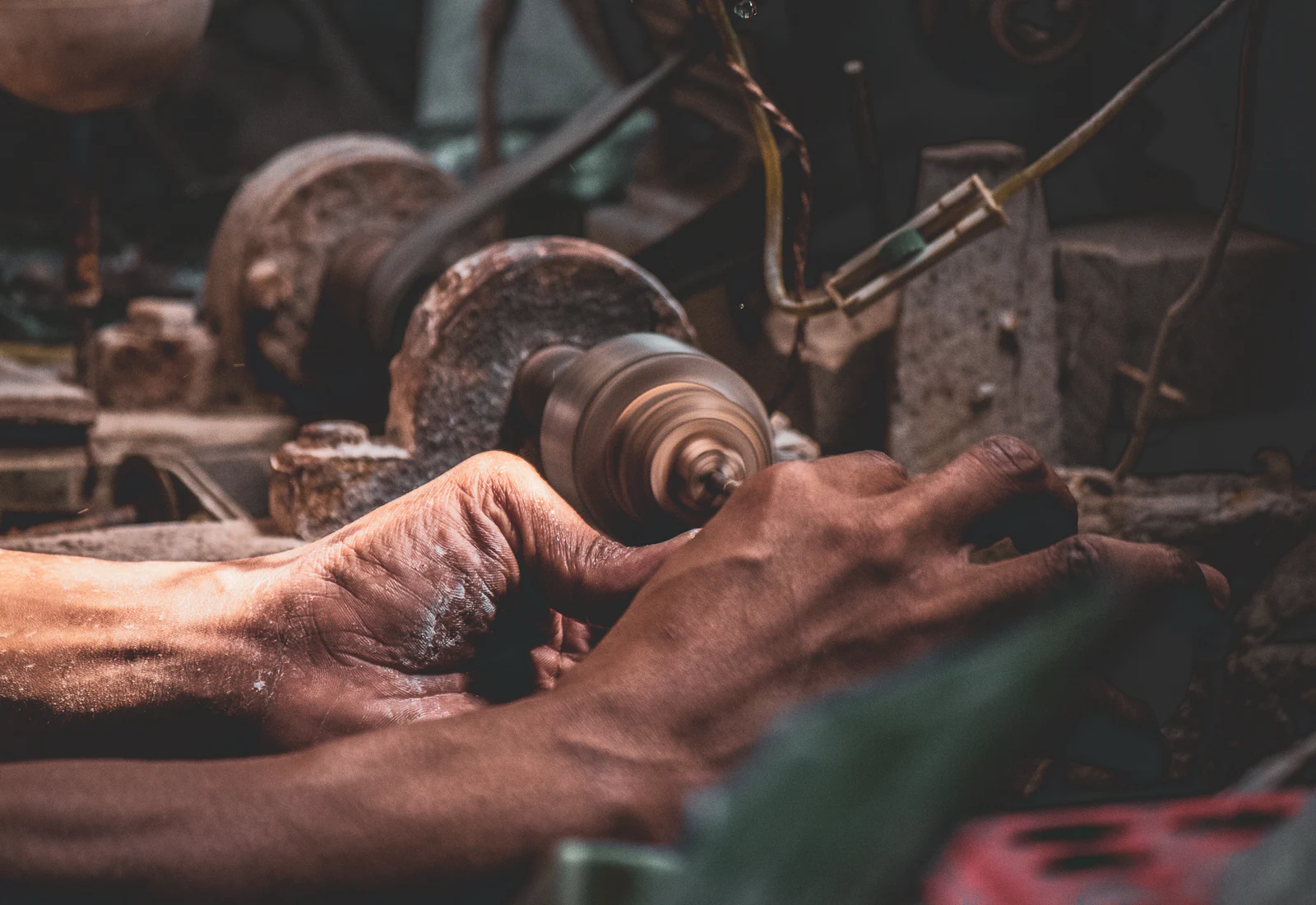 Mains d'artisan façonnant une pièce métallique à l'atelier